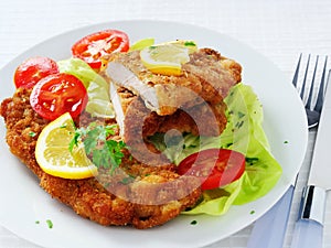 Wiener Schnitzel with potato salad served with lemon slices and parsley