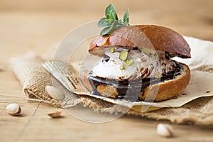 Wierd burger with vanilla ice cream and chocolated confetti on wooden background.