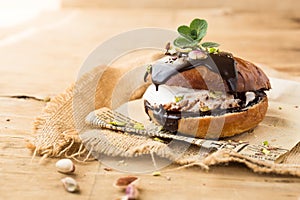 Wierd burger with vanilla ice cream and chocolated confetti on wooden background.