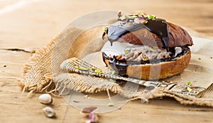 Wierd burger with vanilla ice cream and chocolated confetti on wooden background. photo