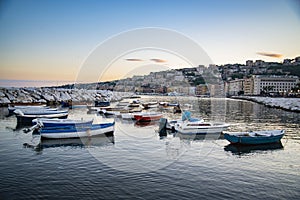 Wiew over fish boats embarked in the bay of Napoli on a gloomy spring evening. Napoli waterfront with Napoli hills and