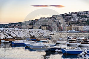 Wiew over fish boats embarked in the bay of Napoli on a gloomy spring evening. Napoli waterfront with Napoli hills and buildings