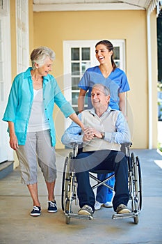 Wife, caregiver laughing or old man in wheelchair in hospital clinic helping an elderly patient for support. Funny