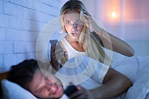 Wife Catching Cheating Husband Chatting On Smartphone Lying In Bed
