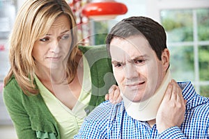 Wife Comforting Husband Suffering With Neck Injury
