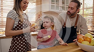 Wife feeding fruit to husband in home kitchen, family relations concept