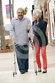 Wife Helping Senior Husband To Use Walking Frame