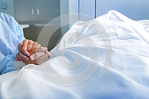 Wife holds the hand of the deceased spouse in the hospital