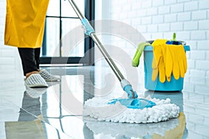 Wife housekeeping and cleaning concept, Happy young woman in blue rubber gloves wiping dust using mop while cleaning on floor at