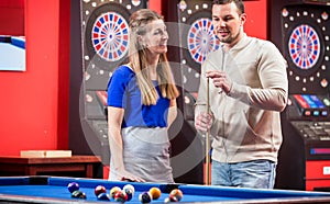 Wife looking at husband while playing billiard