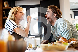 Wife in love feeding her husband and having fun in kitchen