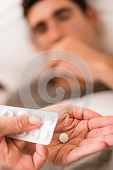 Wife or nurse giving a sick man medication