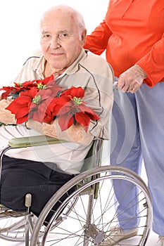 Wife pushing handicap man in wheelchair with flowe