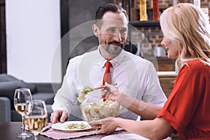 wife putting salad on husband plate during