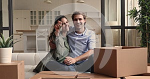 Wife showing keys sitting with husband on couch near boxes