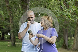 Wife showing something on the smartphone to her husbund after exercising in the mountain in nature