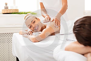 Wife Smiling To Husband During Couples Massage Relaxing In Spa