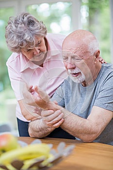 Wife is standing next to her senior husband, who is holding the wrist