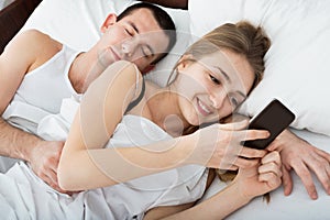Wife texting with lover on smartphone