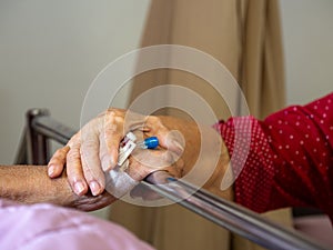 Wife visiting husband in hospital. Senior couple holding hands on hospital bed for hospitalization for supporting his dear. Concep