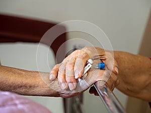 Wife visiting husband in hospital. Senior couple holding hands on hospital bed for hospitalization for supporting his dear. Concep
