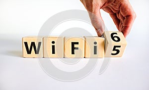 WiFi 5 or 6 symbol. Businessman turns a wooden cube and changes the words WiFi 5 to WiFi 6. Beautiful white background, copy space