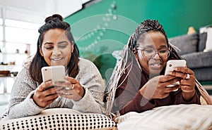 Wifi and friendship, the gifts that keep on giving. two young women using their smartphones on the floor at home.