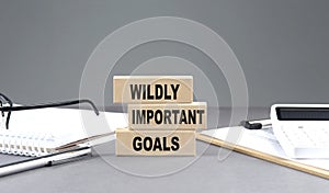 WIG - Wildly Important Goals text on wooden block with notebook,chart and calculator, grey background