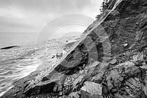 Wild beach, sea and cliff erosion in winter. Black and white