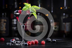 Wild berries alcoholic cocktail drink with vodka, syrup, lemon juice, blueberries, raspberries, blackberries and ice in cocktail