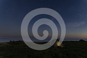 Wild camping in nature in Estonia. Tent on the sea cliff in Paldiski at night, starry sky