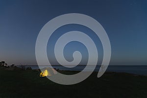 Wild camping with a tent at night in summer. Starry sky, Paldiski cliff