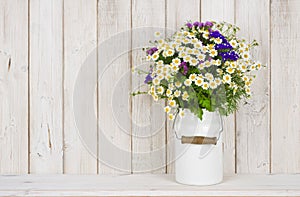 Wild chamomile flowers bouquet on table over wooden planks background