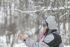 Wild chickadee bird landing on a man`s hands in snowing winter, New England, US