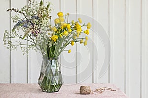 Wild flower bouquet in glass vase on table