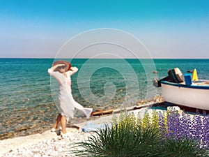 Wild flowers on beach sand fish boat on horizon women in white dress and straw hat blue sky and green sea water tropical landscape