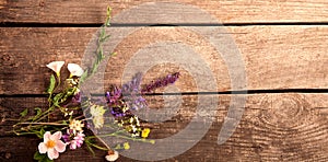 Wild flowers on old grunge wooden background chamomile lupine dandelions thyme mint bells