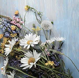 Wild flowers on old grunge wooden background chamomile lupine dandelions thyme mint bells rape