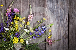 Wild flowers on old grunge wooden background (chamomile lupine dandelions thyme mint bells rape