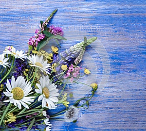 Wild flowers on old grunge wooden background (chamomile lupine dandelions thyme mint bells rape