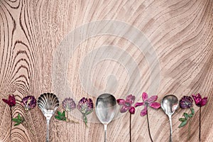 Wild flowers and silver spoons on wooden surface