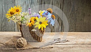 Wild flowers in vase, tangle of rope and scissors on old grunge wooden background chamomile lupine dandelions thyme mint bells