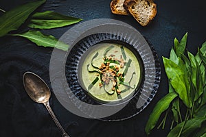 Wild garlic soup with wild garlic leaves and rosted onions on black background