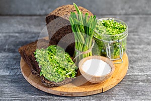 Wild leek pesto on a slice of bread with olive oil and salt on a wooden table with bread. Useful properties of wild garlic. Fresh