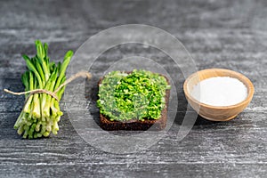 Wild leek pesto on a slice of bread with olive oil and salt on a wooden table with bread. Useful properties of wild garlic. Fresh