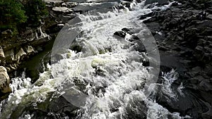 Wild mountain river flowing through stone boulders. Abundant clear stream in carpathians.