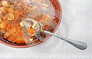 Wild mushroom mushroom soup in a brown clay plate and spoon on linen cloth close-up, copy space