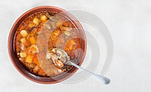 Wild mushroom mushroom soup in a brown clay plate and spoon on linen cloth, top view, copy space