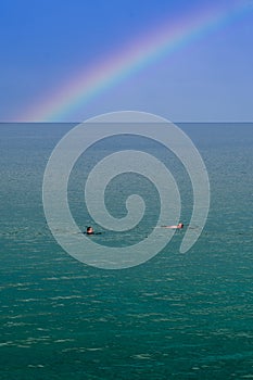 Wild or open water swimming in calm water under a rainbow with copy space