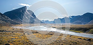 Wild Owl River winds through remote arctic landscape in Akshayuk Pass, Baffin Island, Canada. Moss valley floor and